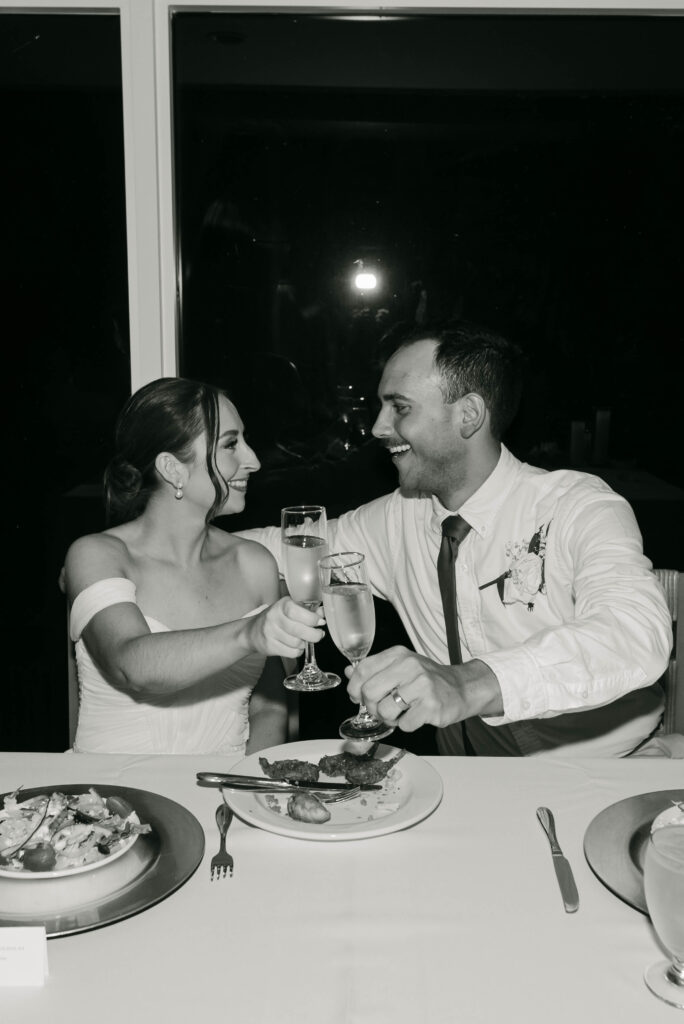 bride and groom saying cheers during the reception in black and white