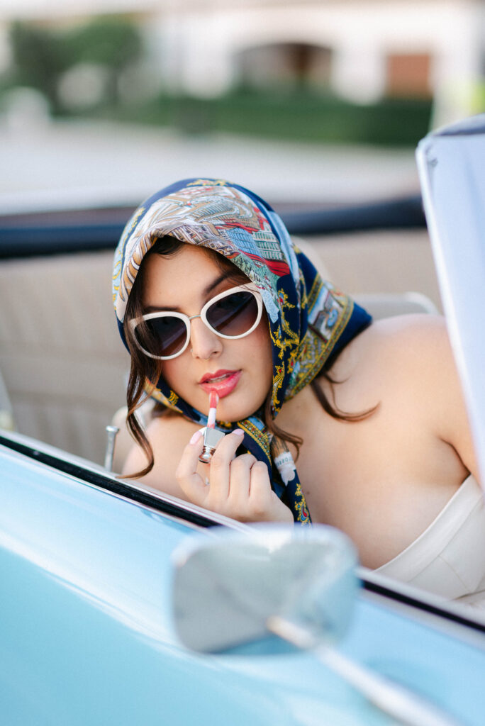 woman fixing her lipstick in a vintage convertible on worth avenue