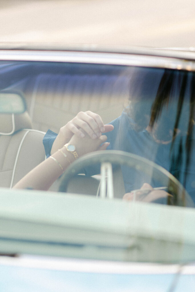 Detail shot of engagement ring as couple holds hands