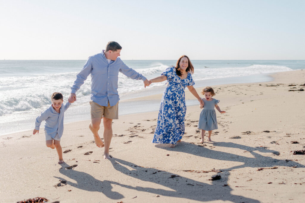 Family of four walking along the beach in bright morning light