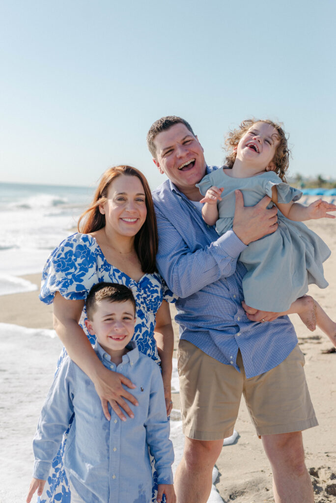 Close-up of parents smiling while cuddling their kids on the beach