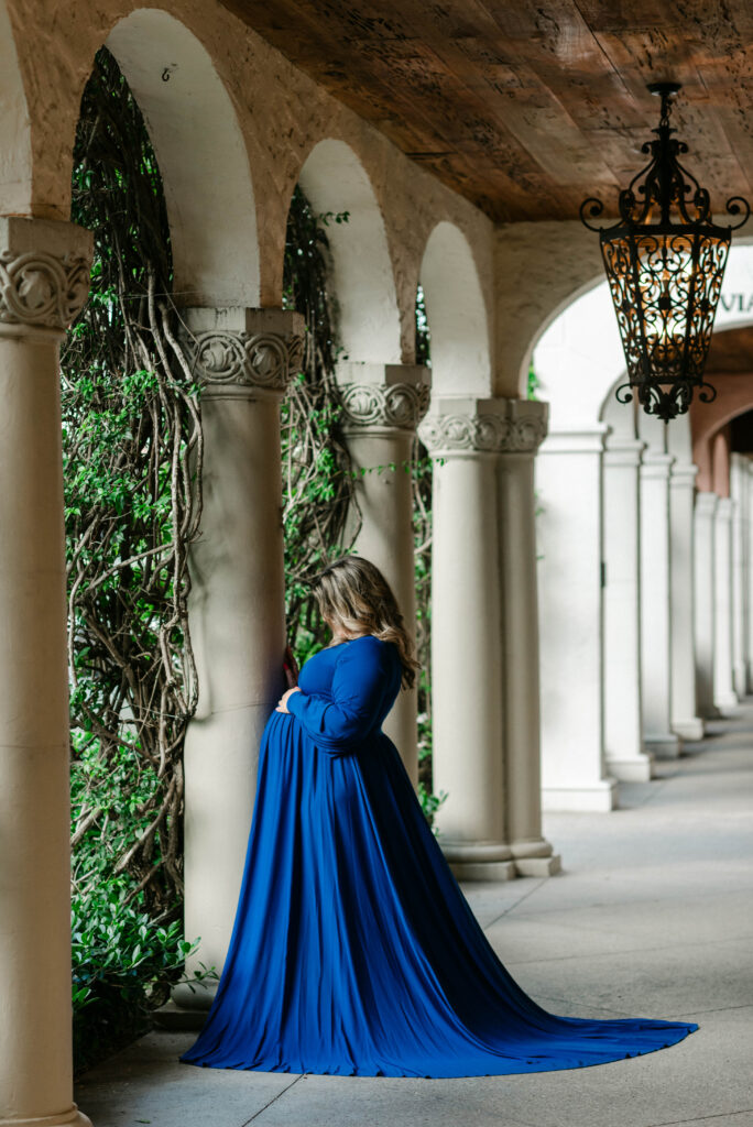Backlit silhouette of pregnant woman under architectural arch
