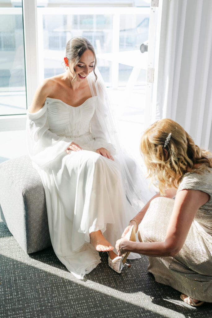 mother of the bride helping her put her shoes on
