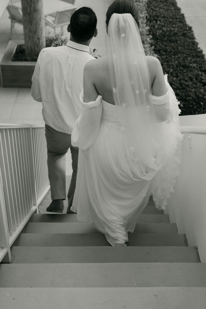 groom leading the bride down the stairs to the beach