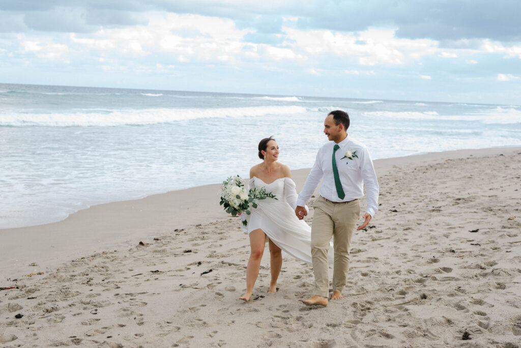 Couple walking barefoot on the sand after the ceremony