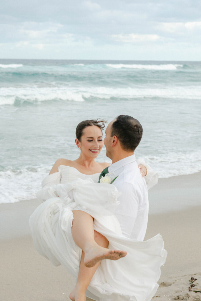 Bride twirling in flowy off-the-shoulder gown by the water