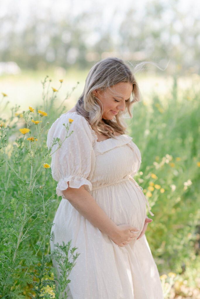 Kelli holding her baby bump in a flowing dress at a South Florida farm maternity session