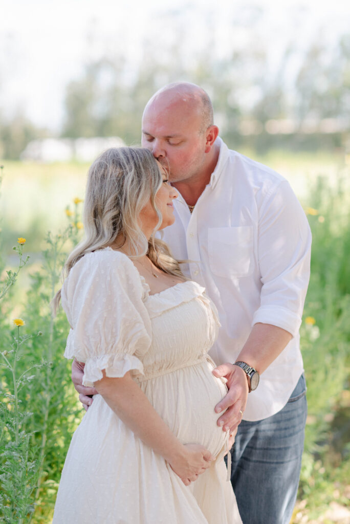 Romantic maternity photo of Jason kissing Kelli’s forehead at Kai-Kai Farm