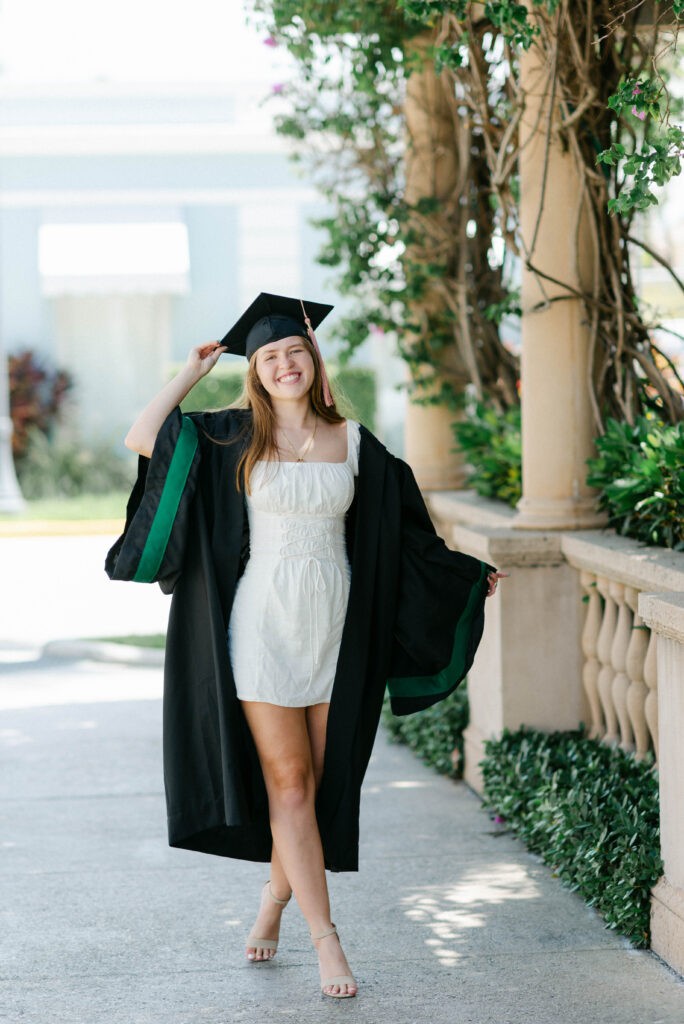 Graduate smiling at camera under Mediterranean-style arch