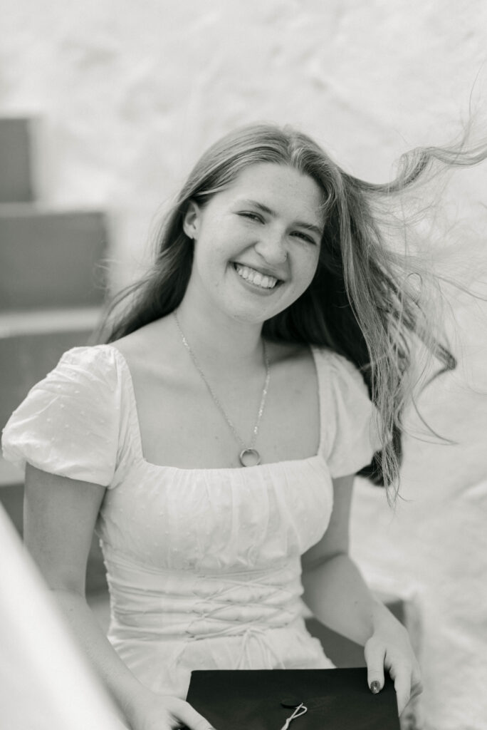 Candid laughing photo of grad in front of stone wall on Worth Avenue