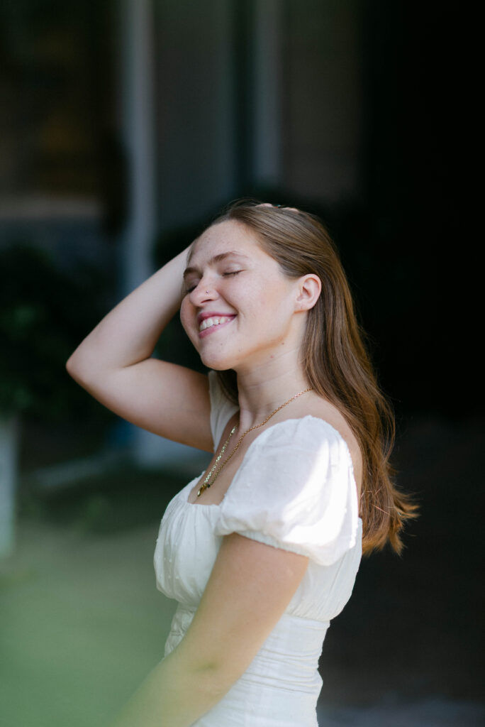 Senior flipping hair with a dark background during grad shoot