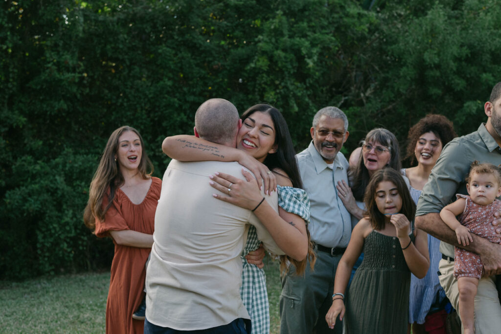 Bride and groom celebrating surprise proposal during outdoor family session in Ocala