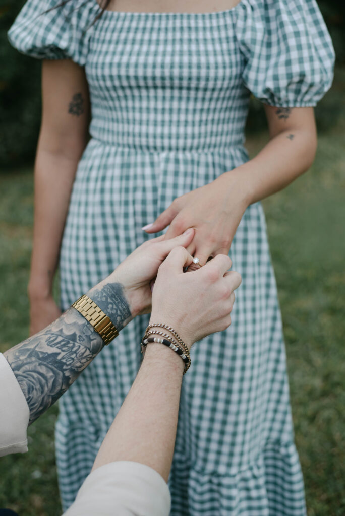Groom puts ring on the bride's finger during a candid backyard family session