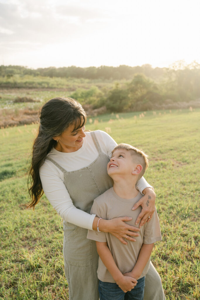 mother and son smiling at each other in a sunny field