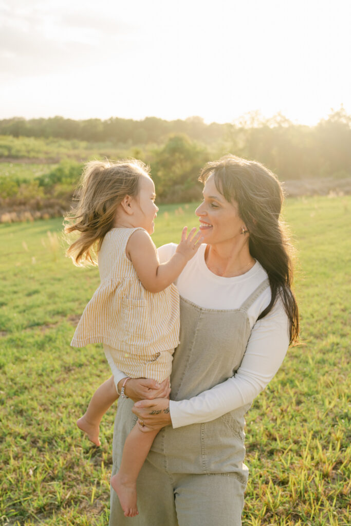 baby girl being held by parents in warm sunset light