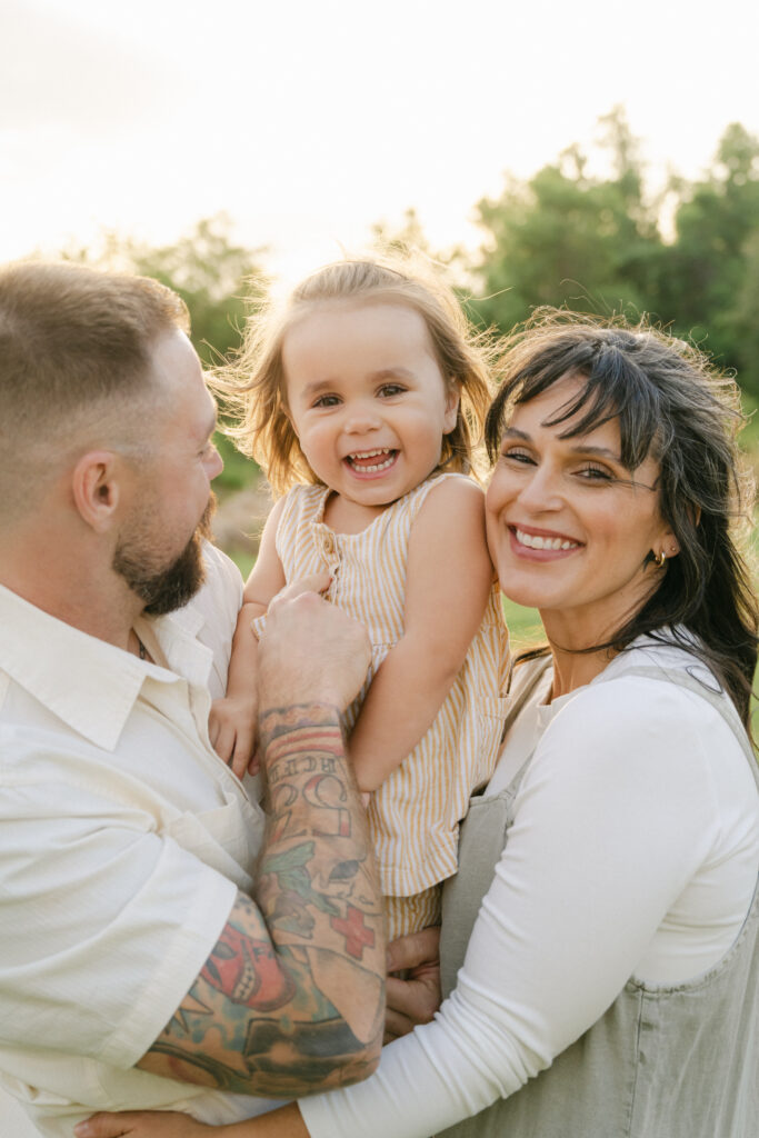 parents smiling and holding baby during golden hour session